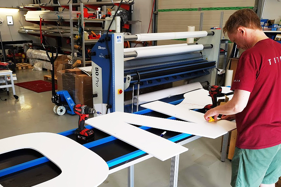 Tausta alumiiniprofiilit maalattu julkisivun värisiksi ja kohokirjaimet asennettavissa 